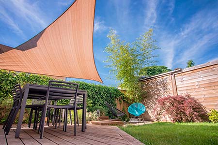 Modern house terrace in summer with table and shade sail